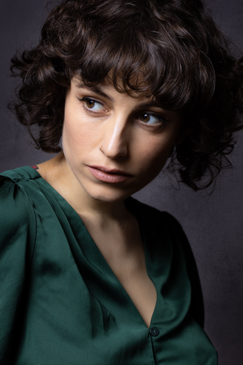 Mel Pettit Photography - Headshot - A dark haired young woman with brown eyes wearing a green blouse and looking off to camera left in a head and shoulders portrait